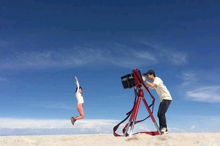 A person jumping in the air with a camera on a tripod on the ground. 4
