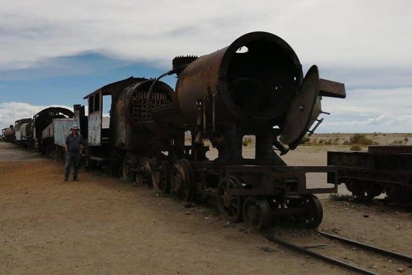Une locomotive rouillée, avec un homme debout à côté, sur une voie ferrée déserte. 5