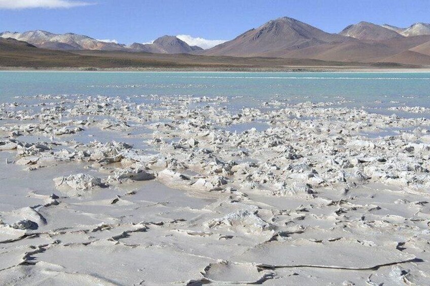 A salt flat with scattered rocks and mountains in the background. 3