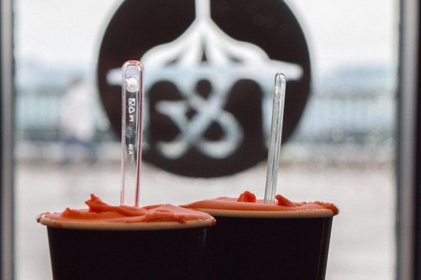 Two cups of iced coffee with straws in front of a window with a logo. 3