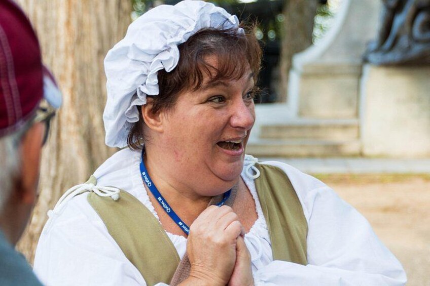 A person in historical costume with a white headscarf and a green vest. 2