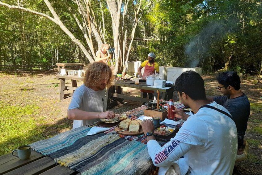 Un picnic al aire libre con gente comiendo y preparando comida. 4