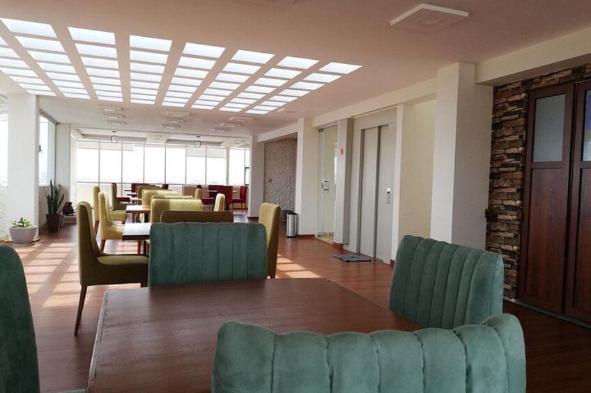 Un espacio interior amplio con suelo de madera, sillas tapizadas en verde y una mesa larga. 5