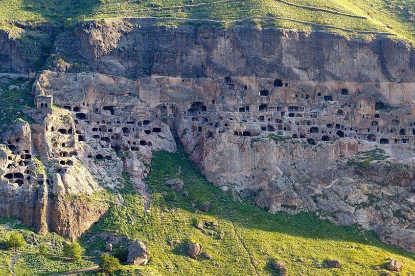 A cliffside with numerous cave dwellings carved into the rock. 2