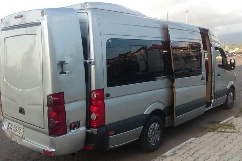 A silver van parked on a paved area with a curb. 2