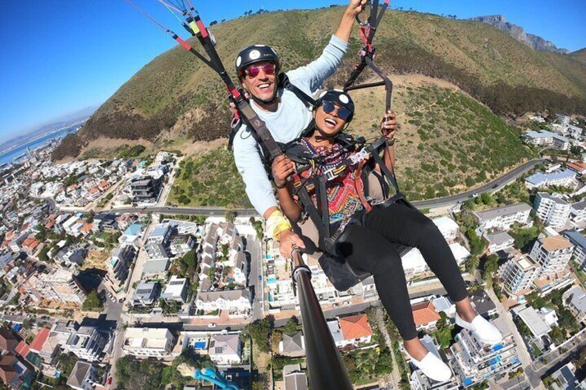 Dos personas practicando parapente sobre una ciudad, con una montaña al fondo. 2