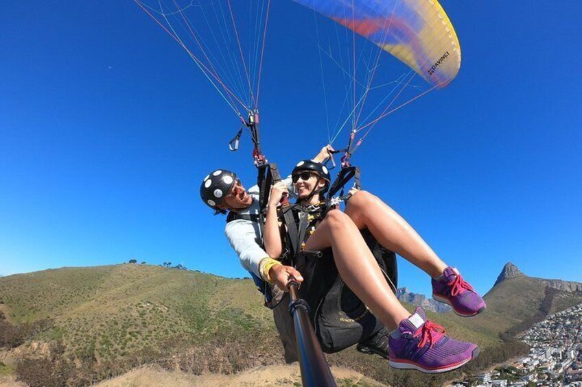 Dos personas haciendo parapente sobre un paisaje montañoso con cielos despejados. 4