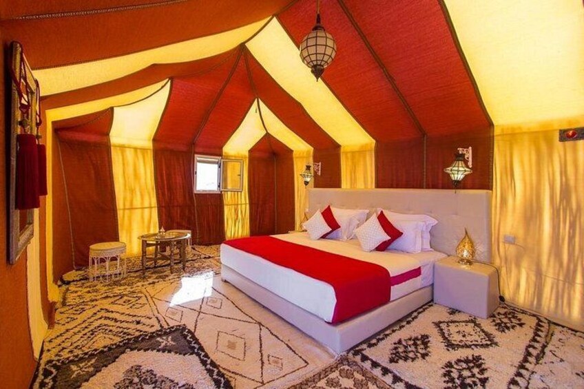 A tented room with a bed, a small table, and a chair. 3