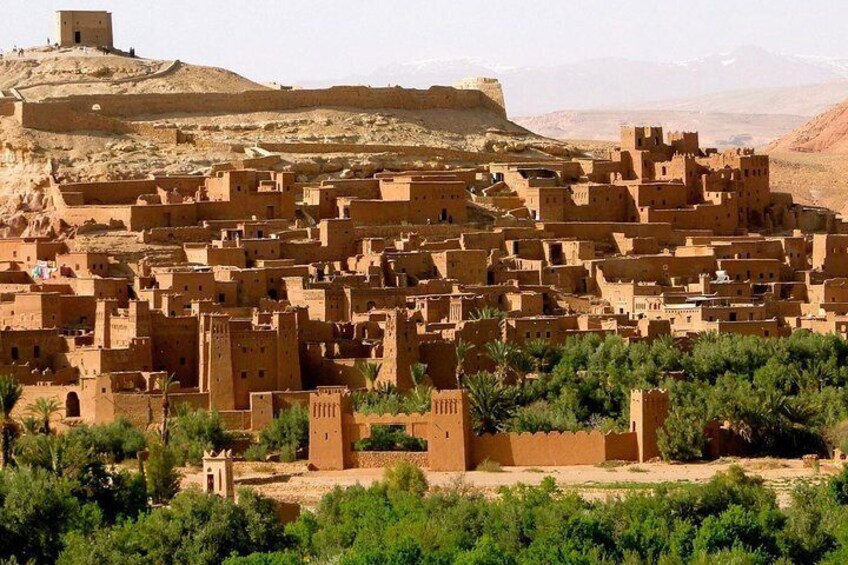 A traditional village with adobe buildings, a prominent tower, and a hill in the background. 2