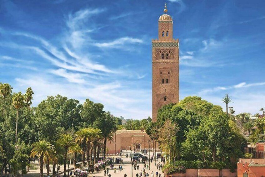 A historic tower with a minaret, surrounded by palm trees and a clear blue sky. 4