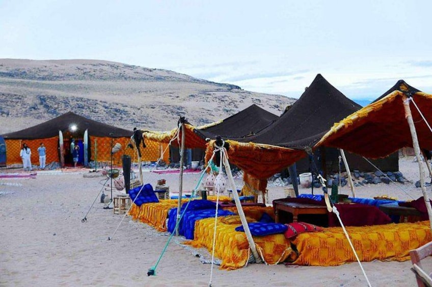 A desert campsite with tents and colorful blankets. 2