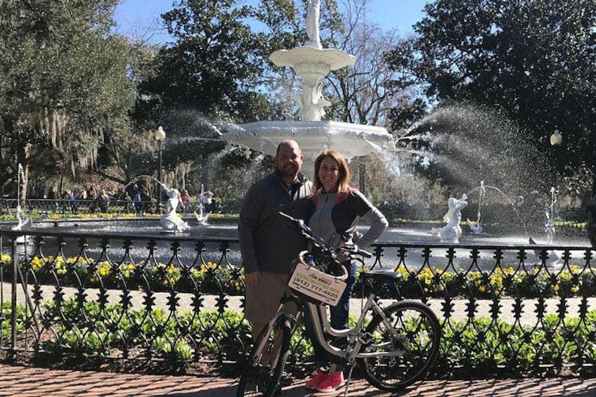 A couple standing by a fountain with a bicycle in the foreground. 2