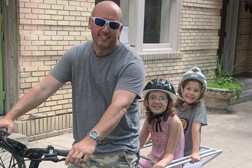A man on a bicycle with two children beside him. 4