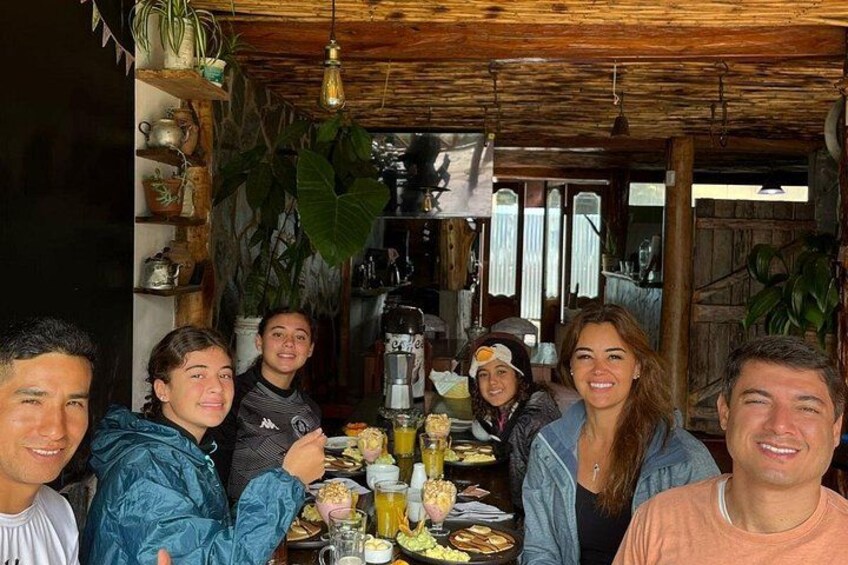 Un grupo de personas cenando en una mesa de madera rústica con varios platos y bebidas. 2