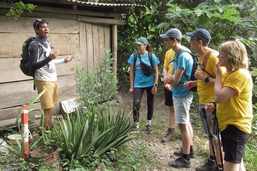 Un grupo de personas vestidas para actividades al aire libre, de pie sobre un sendero de tierra con vegetación circundante, cerca de una estructura de madera. 5