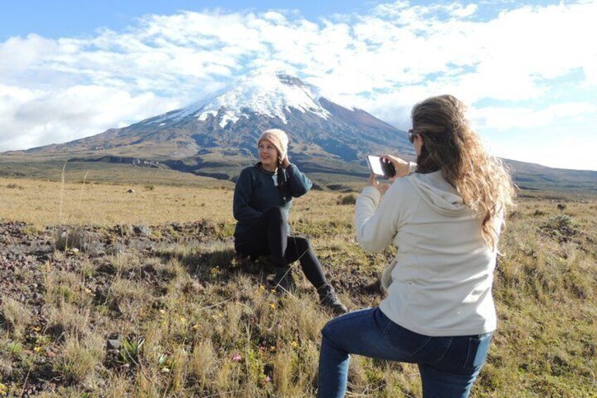 Two people sitting on a grassy field with a snow-capped mountain in the background. 2