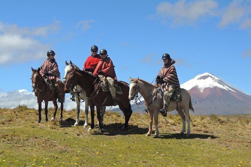 Four people on horseback with a snow-capped mountain in the background. 1