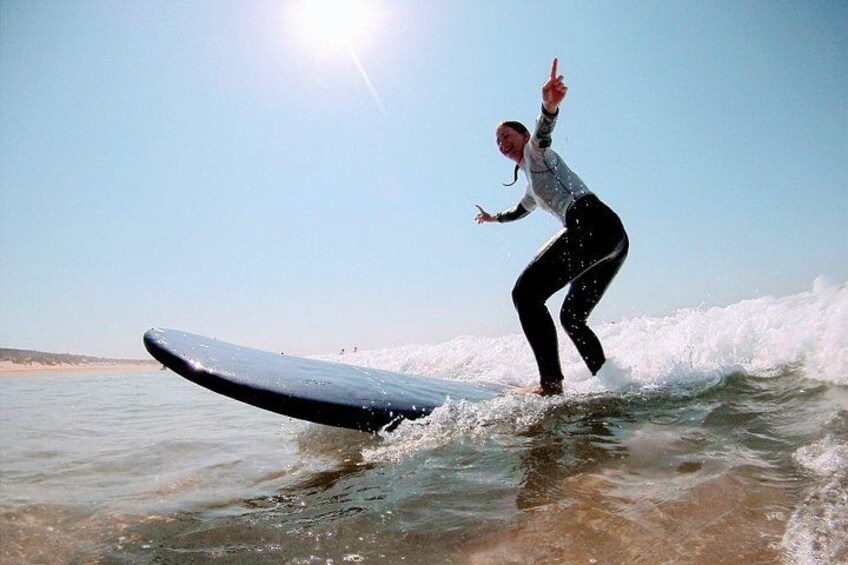 A person surfing on a wave with a clear sky and sun in the background. 3