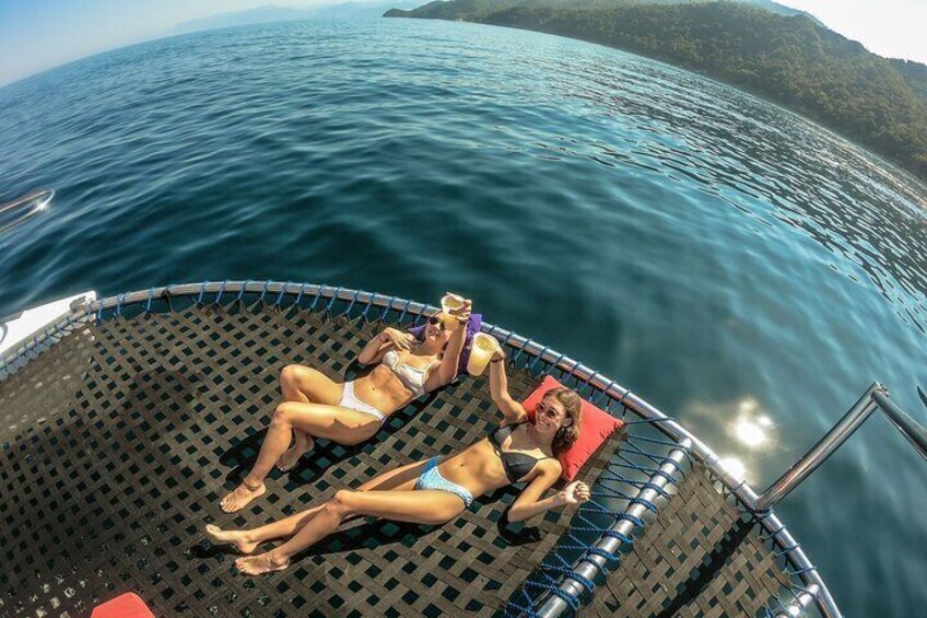 Two people sunbathing on a boat with a view of the sea and a distant island. 2