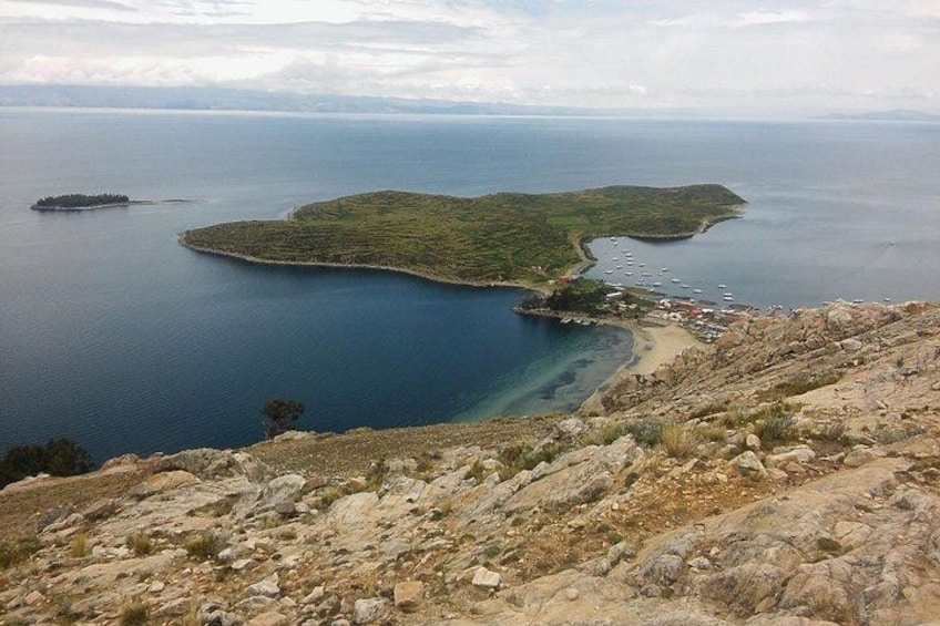 A coastal landscape with a rocky terrain, a small island, and a bay with boats. 5