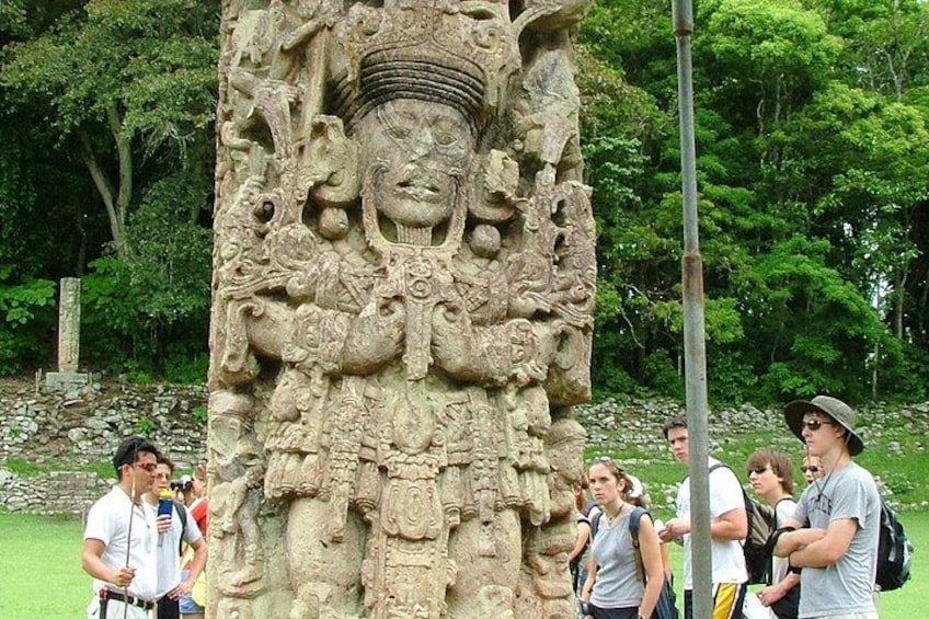 A large stone carving of a deity with multiple arms and a headdress, surrounded by tourists. 3