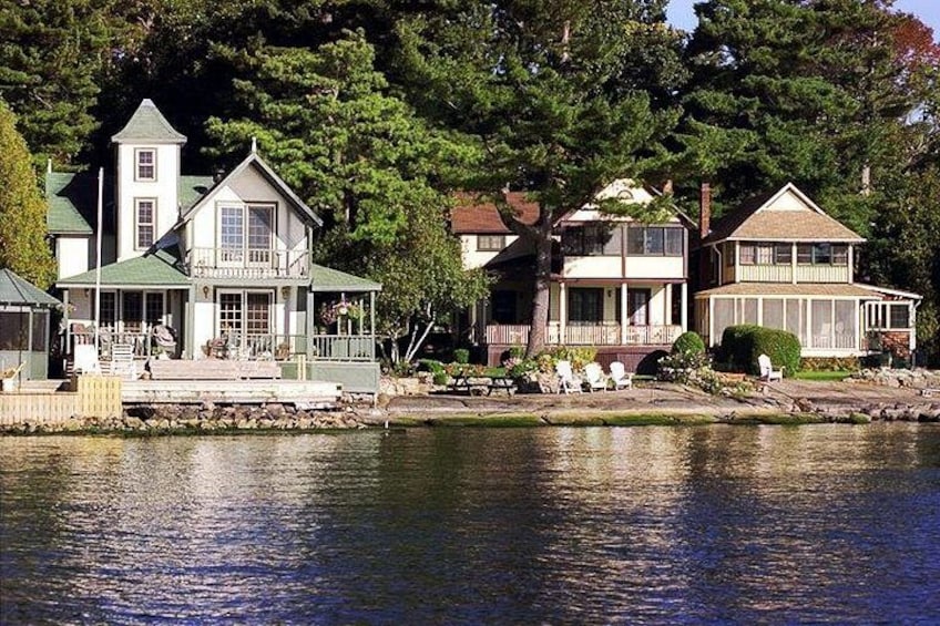 A lakeside property with a dock, a large house with a tower, and a smaller house with a porch. 3