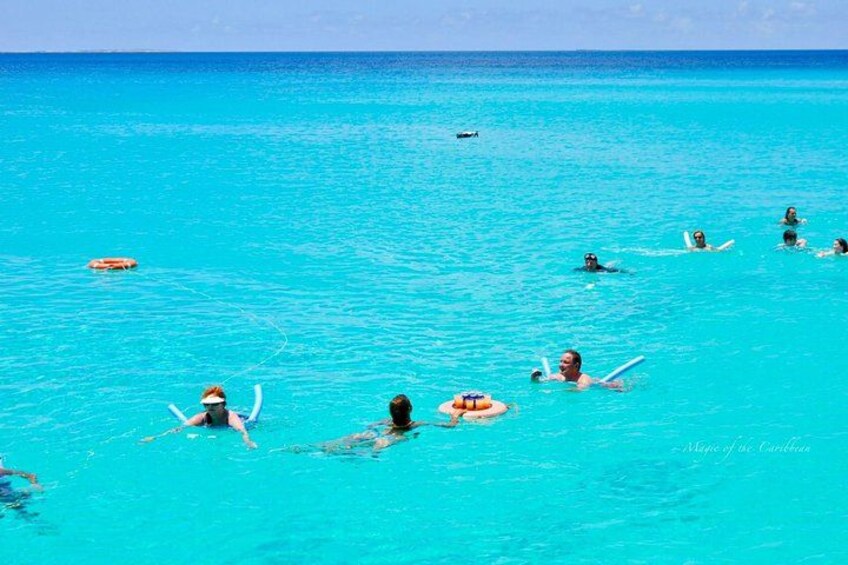 People swimming and surfing in turquoise ocean water. 1