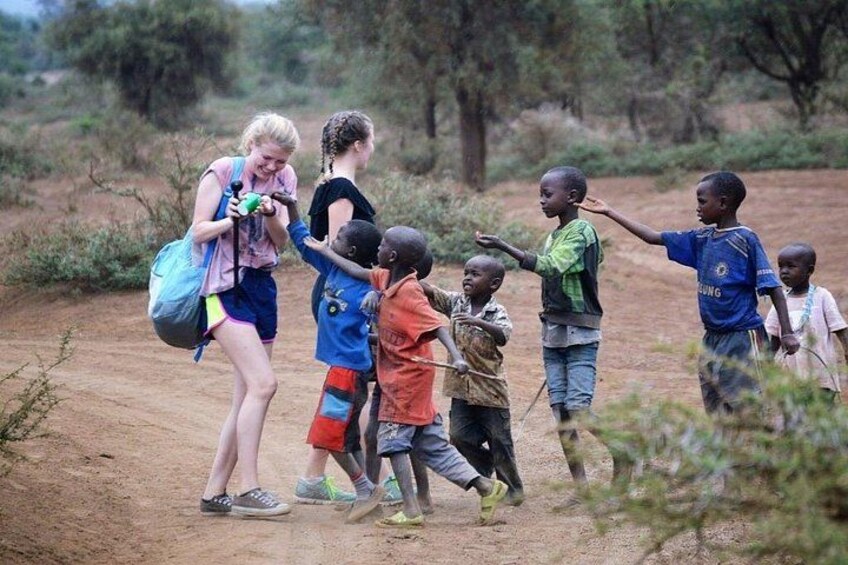 A group of children and adults walking on a dirt path in a natural setting. 4