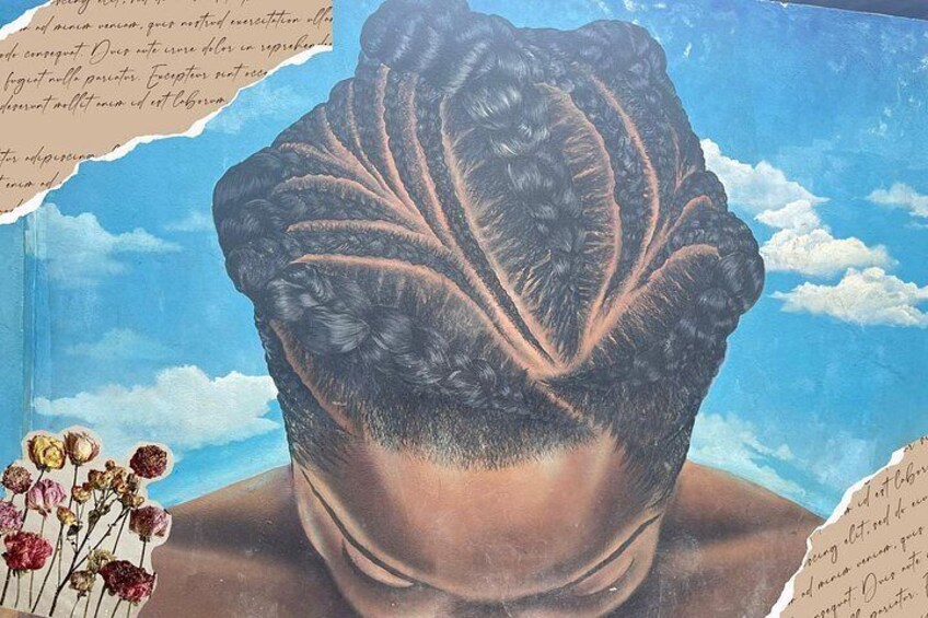 A mural of a person with intricate braiding, a clear sky, and a few flowers. 3