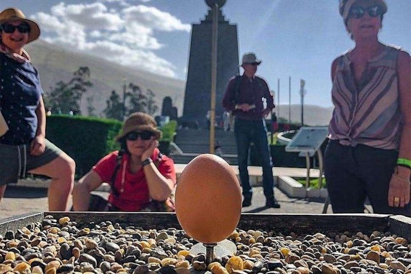 A group of people near a large egg sculpture in an outdoor setting. 4