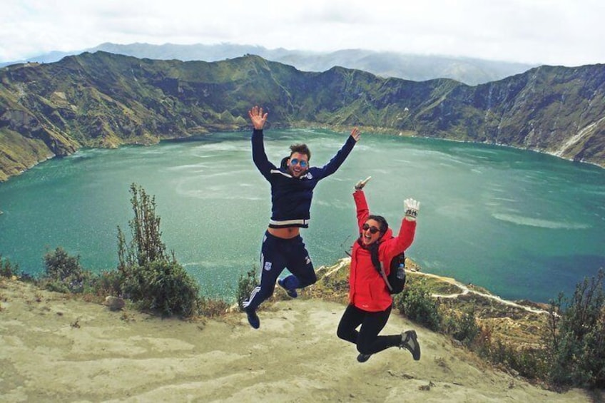 Dos personas saltando por un sendero de tierra, con un lago y montañas al fondo. 5