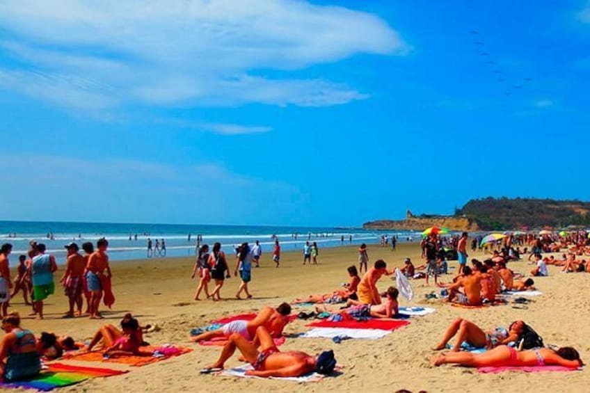 A crowded beach with people sunbathing and walking. 1