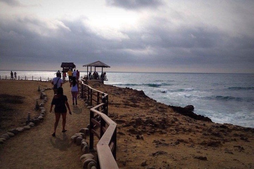 A beach with a wooden walkway, a gazebo, and people walking along the path. 5