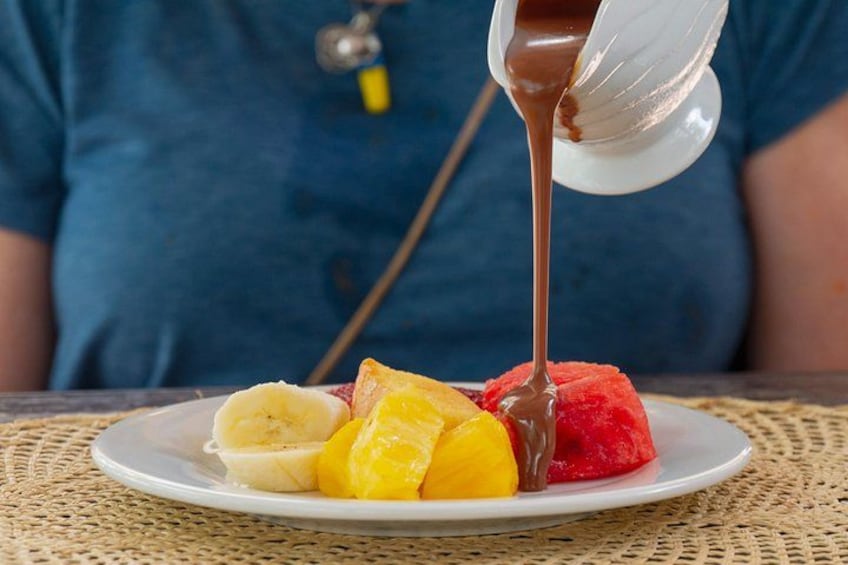 Ein Dessert, über das Schokoladensauce gegossen wird, mit einer Person im Hintergrund. 3