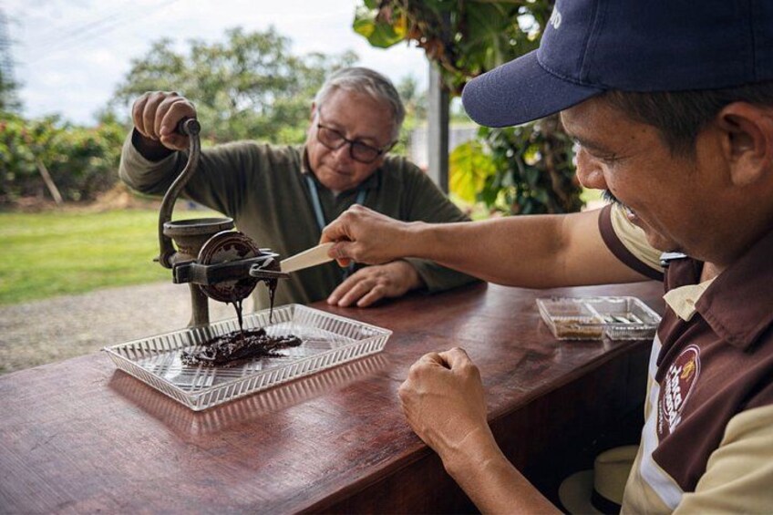 Dos personas en una mesa de madera con una prensa de chocolate. 2