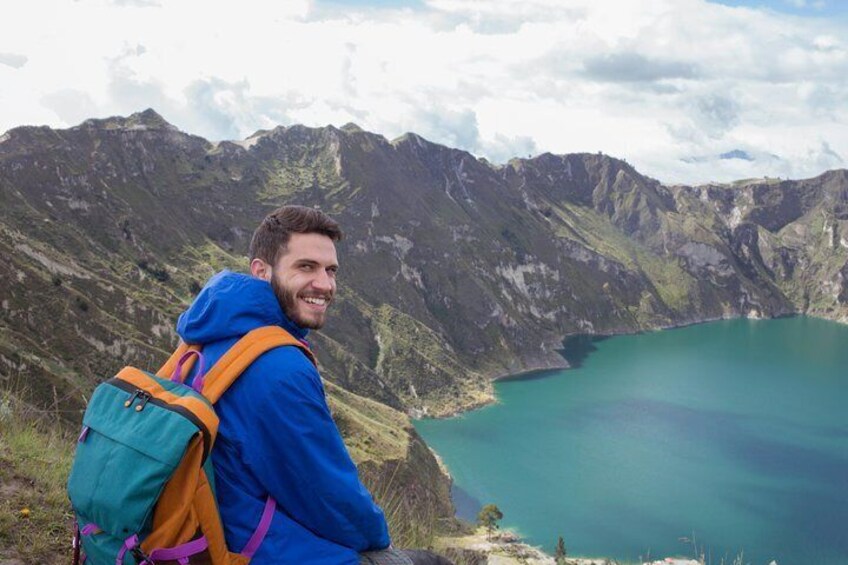 A person with a backpack overlooking a mountainous landscape and a turquoise lake. 1