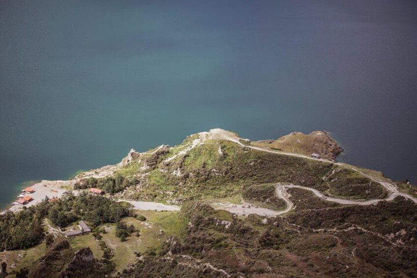 A coastal landscape with a winding road, a small settlement, and a large body of water. 5