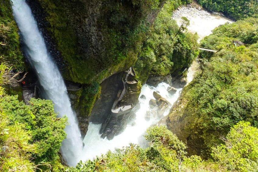 Een waterval stort neer over een met mos begroeide klif, omringd door weelderige begroeiing. 2