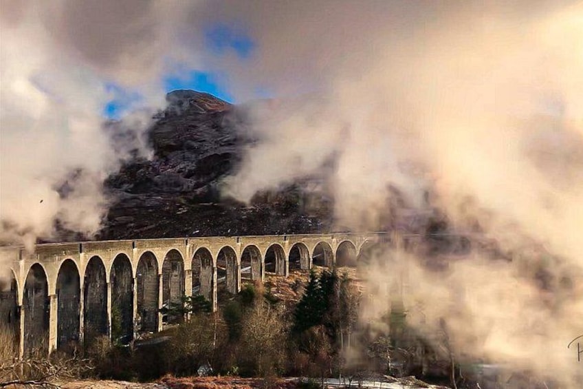 A bridge with arches, a mountain in the background, and clouds partially obscuring the view. 1