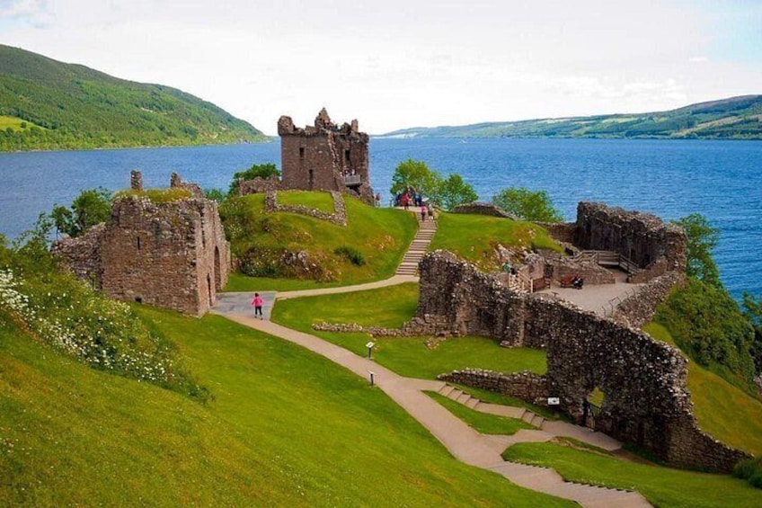 Les ruines d’un château historique, situées au bord d’un lac, sont accessibles par un sentier bordé d’herbe. 4