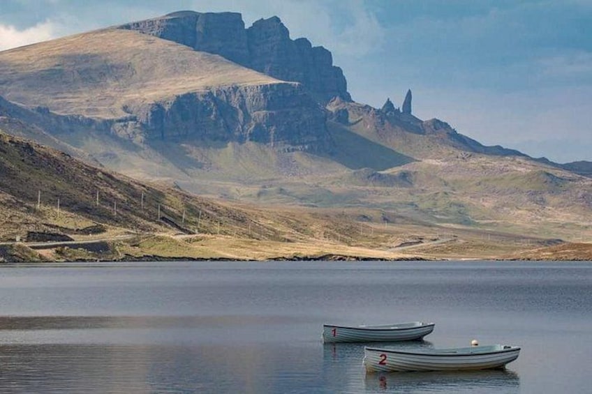 A calm lake with two boats, a mountainous landscape, and a clear sky. 2