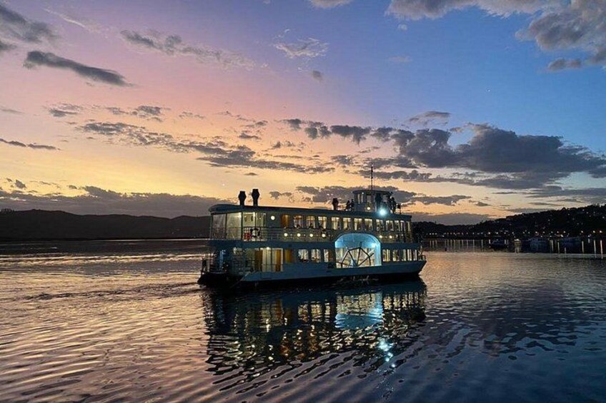 A multi-deck boat on calm water with a sunset sky. 3