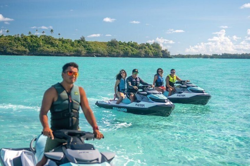 A person on a jet ski with others in the background on a clear turquoise sea. 1
