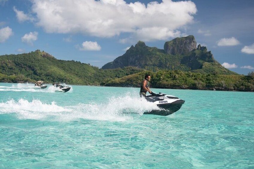 A person jet-skiing on turquoise water with a mountainous landscape in the background. 5