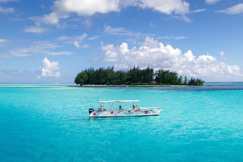 A boat on turquoise water with a small island in the background. 2