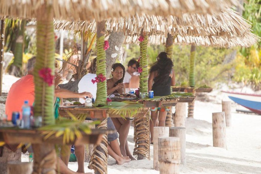 A beach with thatched umbrellas and wooden tables. 4