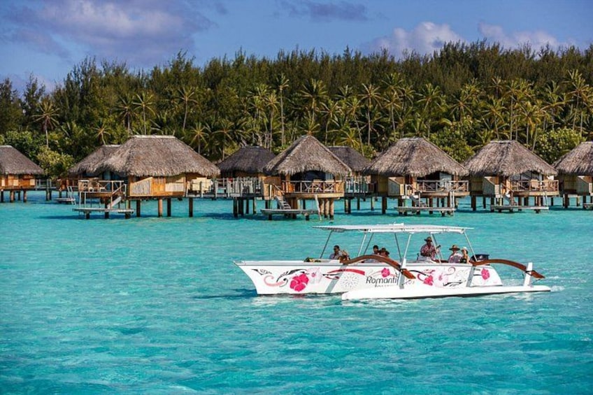 A boat on turquoise water with overwater bungalows in the background. 3