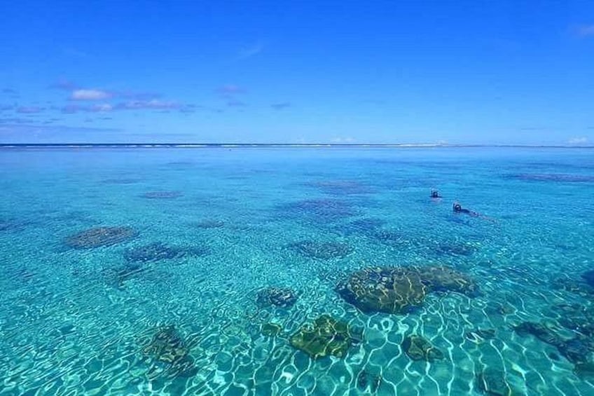 Clear turquoise water, coral reefs, and two people swimming. 3