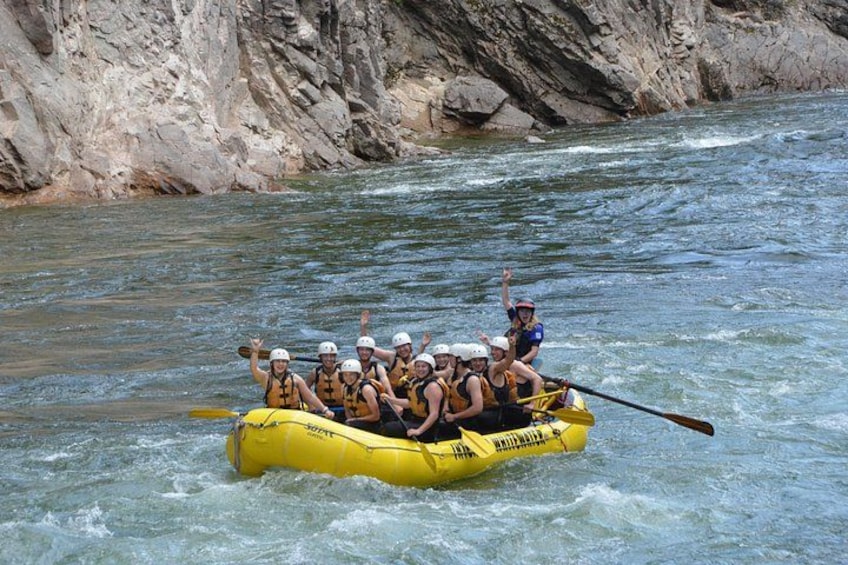 A group of people in a yellow raft on a river surrounded by rocky cliffs. 3