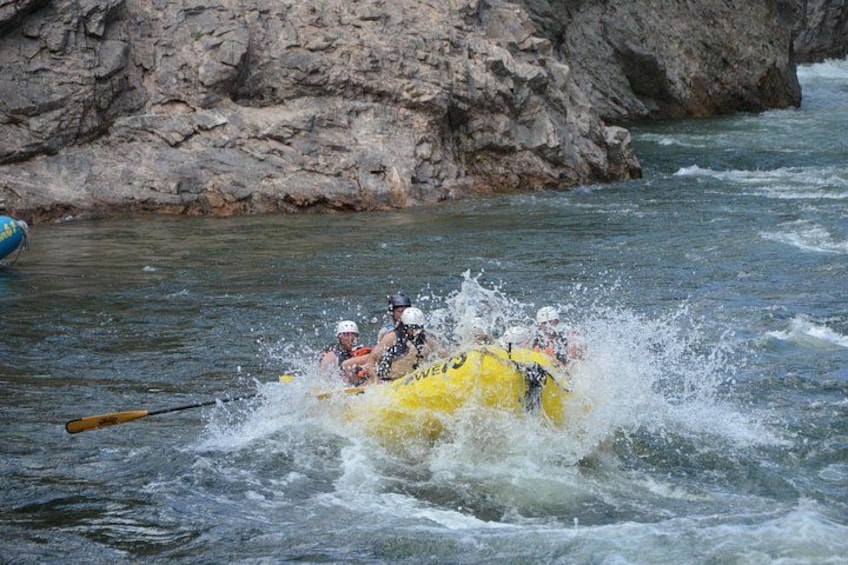 A group of people in a yellow raft navigating through a river with rapids. 4